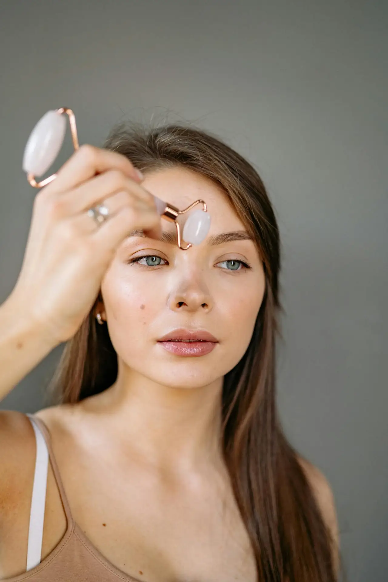 Close-up of a woman using a jade roller on her face, promoting self-care and skincare routines.